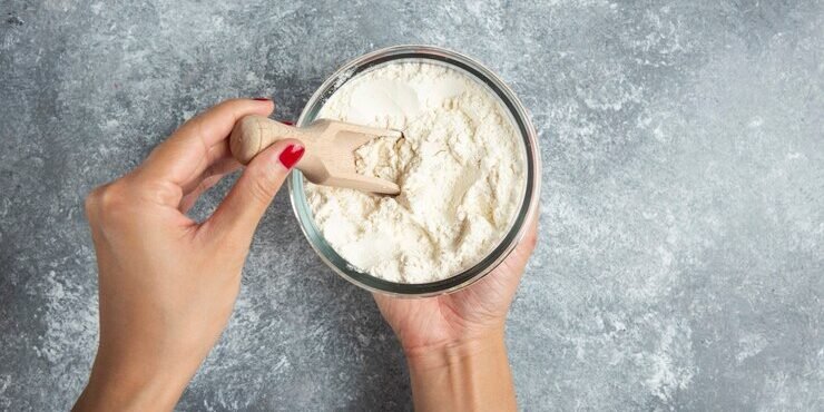 mao-de-uma-mulher-segurando-a-colher-dentro-da-tigela-de-farinha_114579-31394