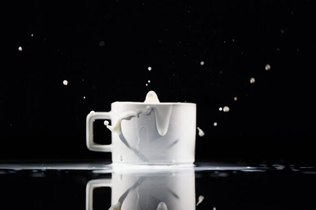 Milk splashes in white cup on black background