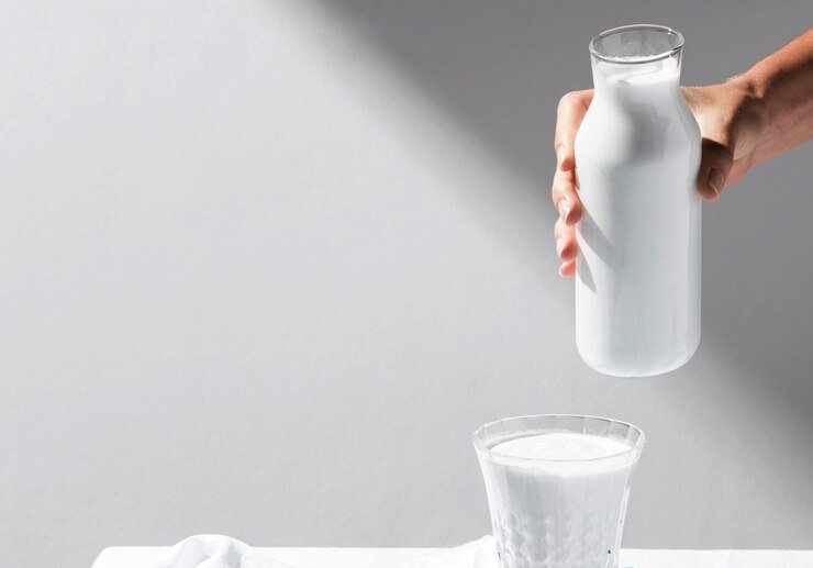 alto-angulo-da-pessoa-servindo-leite-em-copo-com-nozes-na-bandeja_23-2148667727